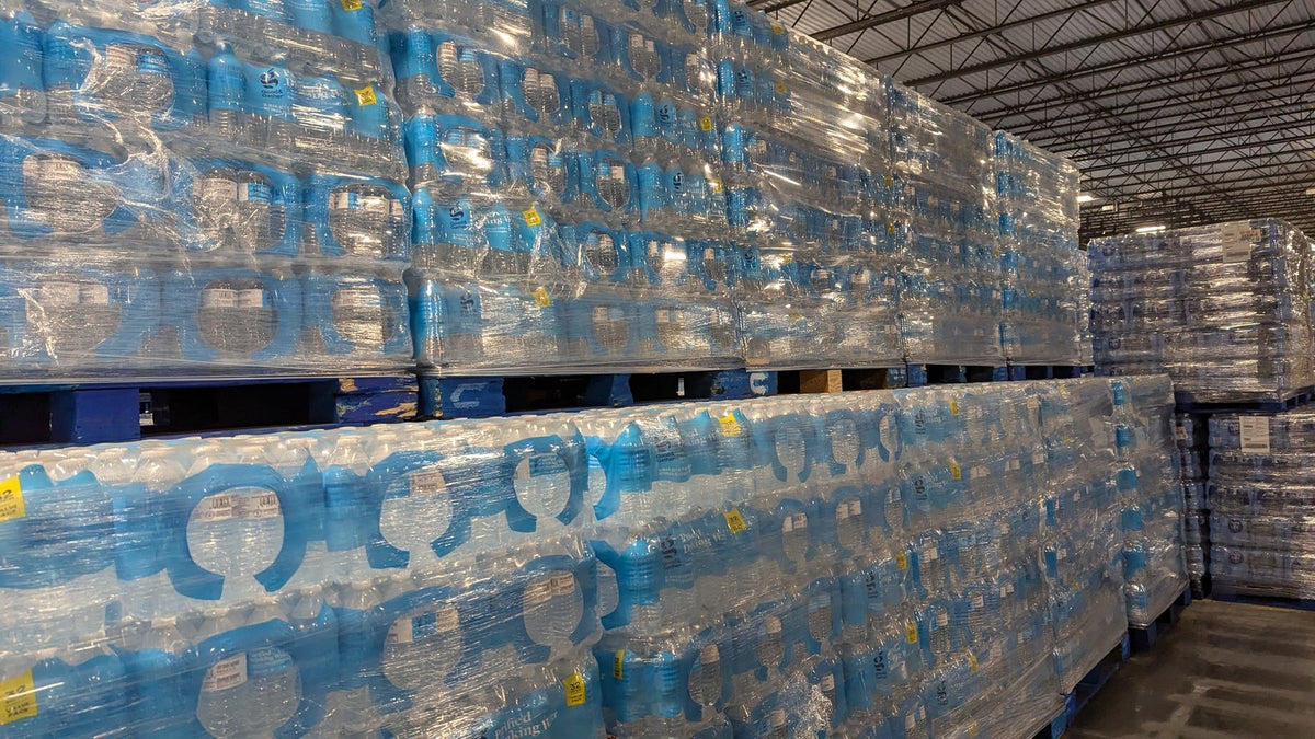 Pallets of shrink-wrapped bottled water cases stacked in a warehouse